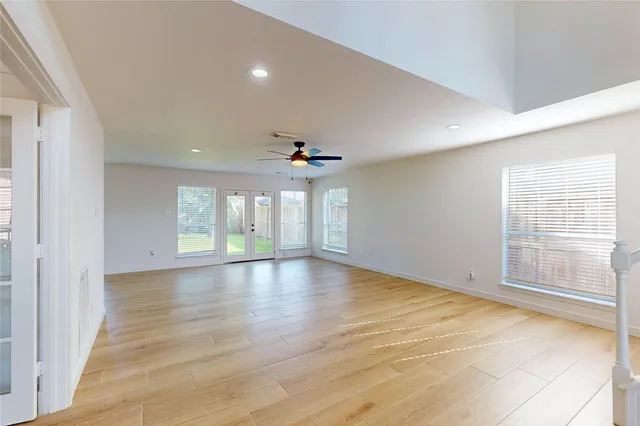 an empty room with wooden floor and windows