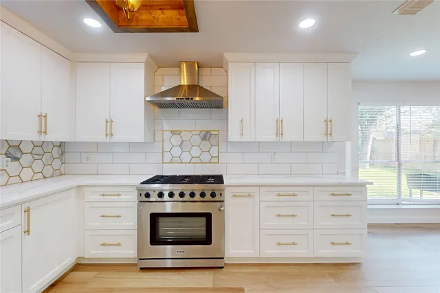 a kitchen with stainless steel appliances a stove and white cabinets