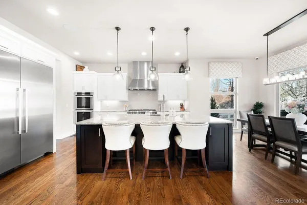 a view of a dining room and livingroom with furniture wooden floor kitchen chandelier