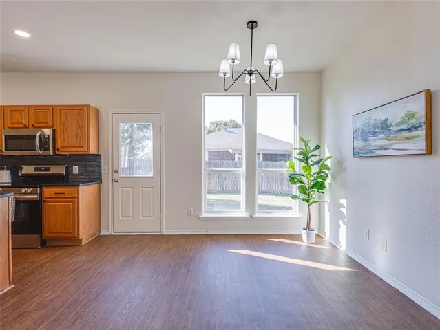 a view of a room with wooden floor chandeliers and kitchen