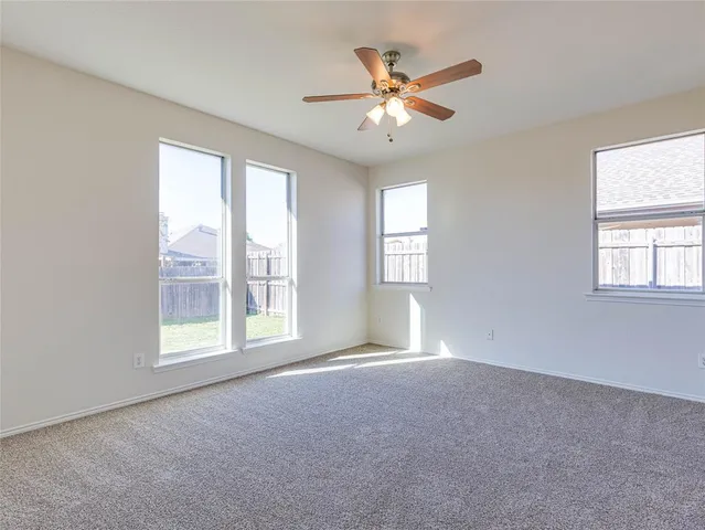 a view of an empty room with chandelier fan and fire place