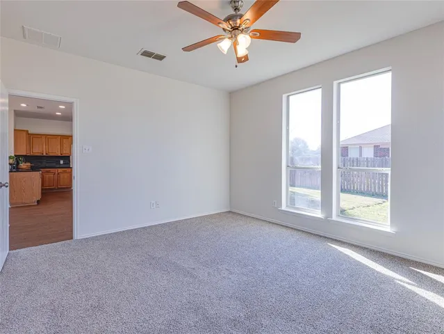 an empty room with chandelier fan and windows