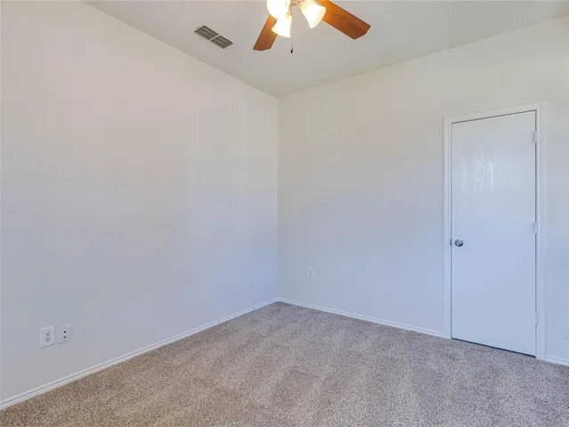 an empty room with a ceiling fan and carpet