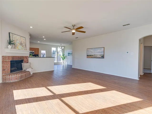 a view of a livingroom with a fireplace a ceiling fan and wooden floor