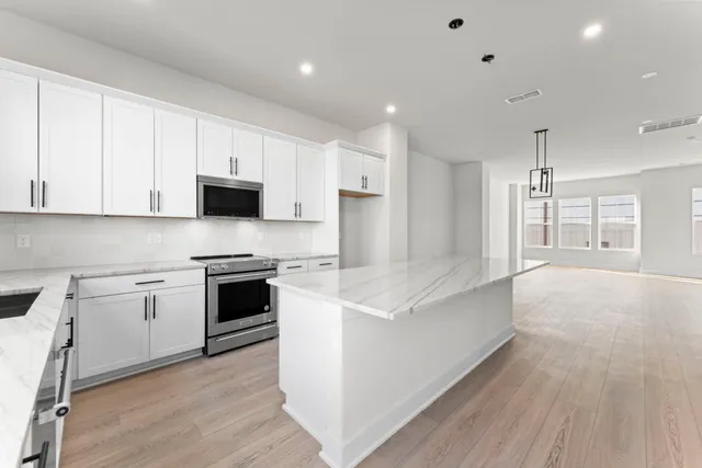 a large kitchen with stainless steel appliances granite countertop a stove and a sink