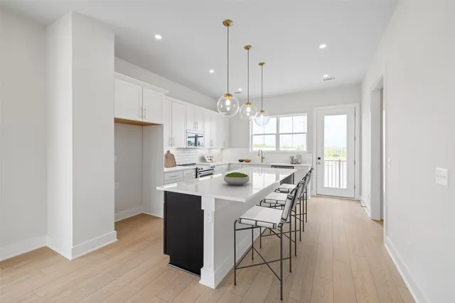 a kitchen with stainless steel appliances kitchen island granite countertop a table chairs a sink a window and cabinets