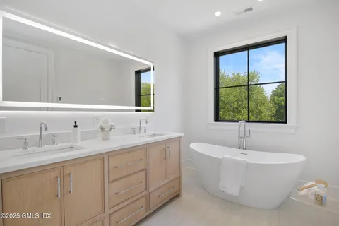 a bathroom with a white tub a sink and window