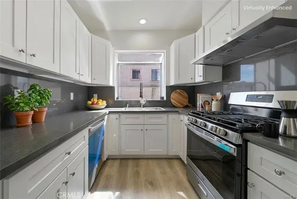 a kitchen with stainless steel appliances granite countertop a stove a sink and a white cabinets