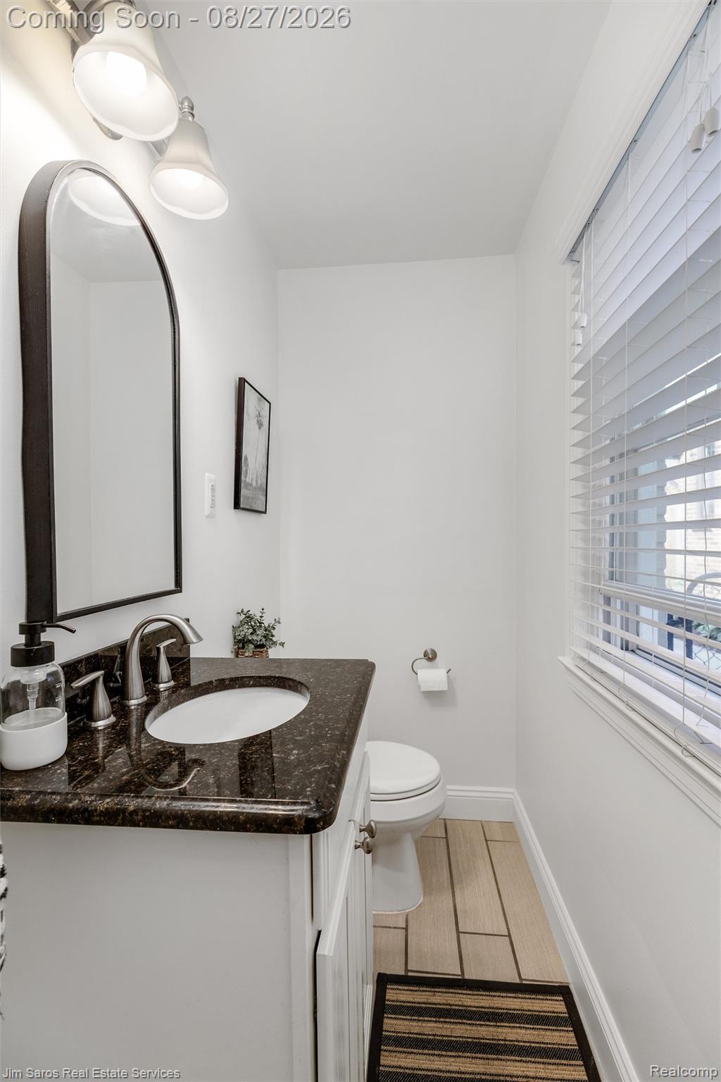 276 Moran Road Grosse Pointe, MI 48236 - Photo 11 of 23 White vanity with a dark speckled countertop, undermount sink, and arch-top mirror