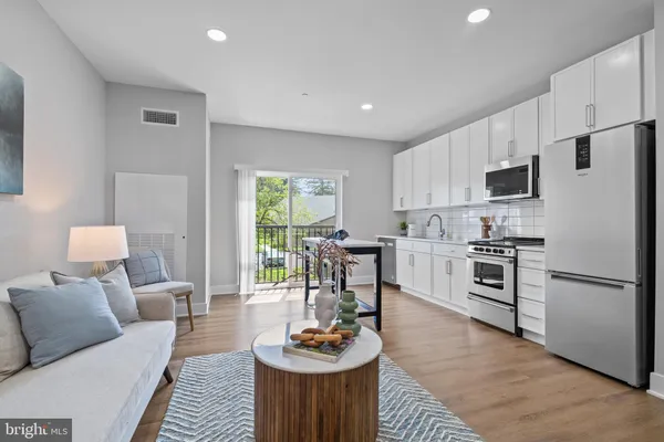 a kitchen with stainless steel appliances kitchen island granite countertop a refrigerator a stove a sink a dining table and chairs with wooden floor