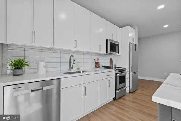 a kitchen with white cabinets and stainless steel appliances