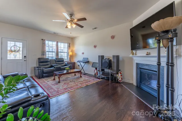 a kitchen with stainless steel appliances granite countertop wooden cabinets a refrigerator a sink a stove and a wooden floors