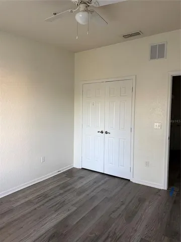 an empty room with wooden floor fan and windows