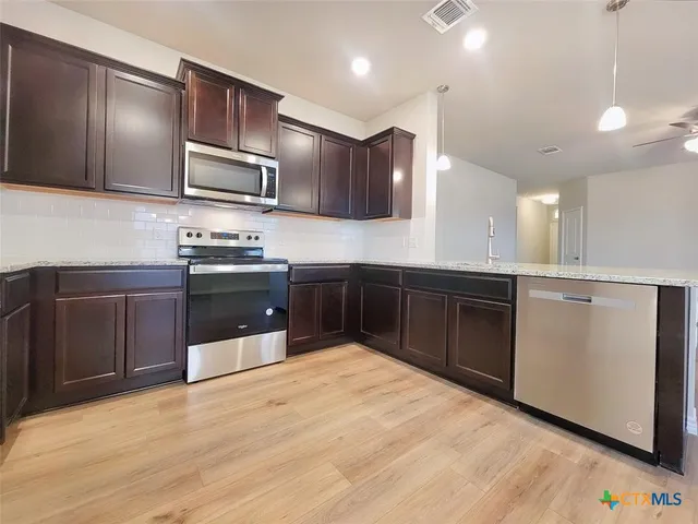 a large kitchen with stainless steel appliances and wooden cabinets