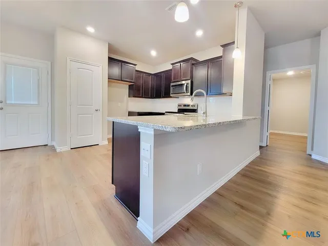 a view of kitchen with stainless steel appliances kitchen island a sink dishwasher a refrigerator and a stove with wooden floor