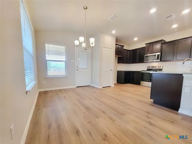 a large kitchen with kitchen island a sink dishwasher a refrigerator and wooden floor