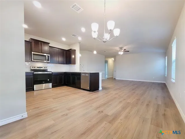 a large kitchen with kitchen island a island wooden floor stainless steel appliances and cabinets