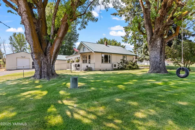 a white house that has a tree in front of a house