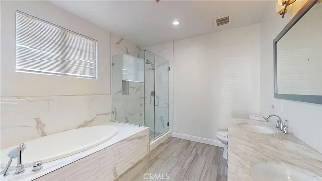 a bathroom with a granite countertop bathtub a sink and a large mirror
