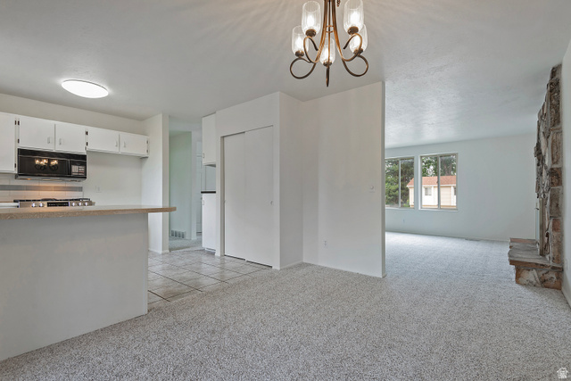 1722 Kimsbrough Road Sandy, UT 84092 - Photo 10 of 29 Open-concept living area featuring light-toned carpeting, a stone fireplace, and a kitchen peninsula with white cabinetry