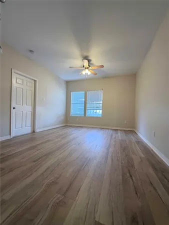 a view of an empty room with a window and wooden floor