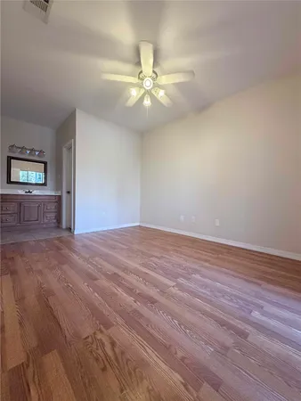 an empty room with wooden floor fan and windows
