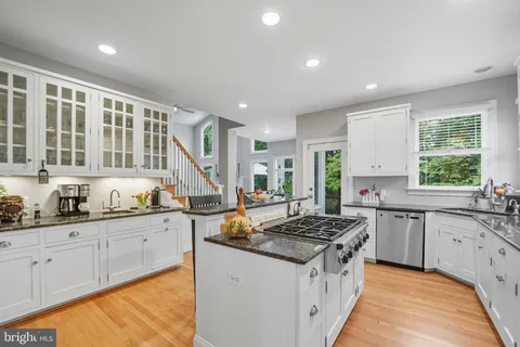a view of a hallway with wooden floor and a bathroom