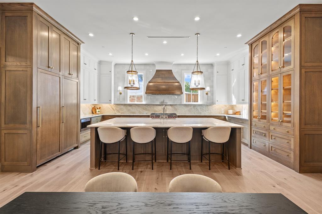 5925 Williamstown Road Dallas, TX 75230 - Photo 10 of 39 Kitchen with brown cabinetry, hanging light fixtures, a breakfast bar area, a large island, and recessed lighting