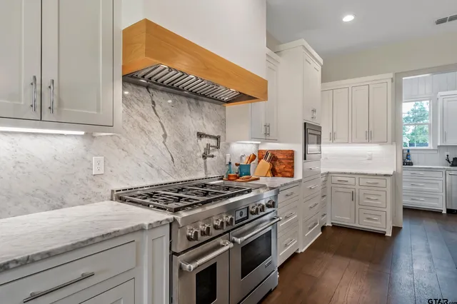 a kitchen with stainless steel appliances granite countertop a stove and a wooden cabinets