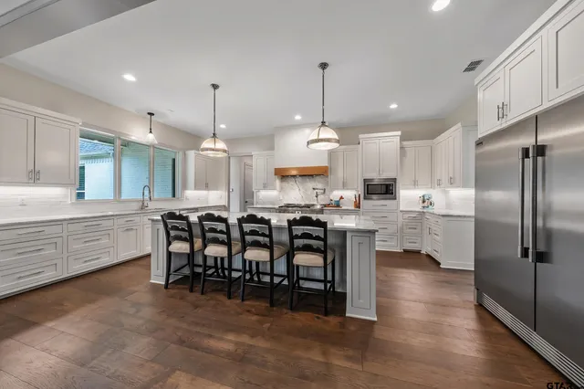 a kitchen with stainless steel appliances kitchen island granite countertop a table chairs sink and cabinets
