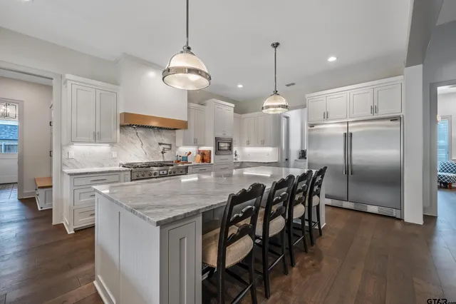 a kitchen with stainless steel appliances a dining table chairs stove refrigerator and wooden floor