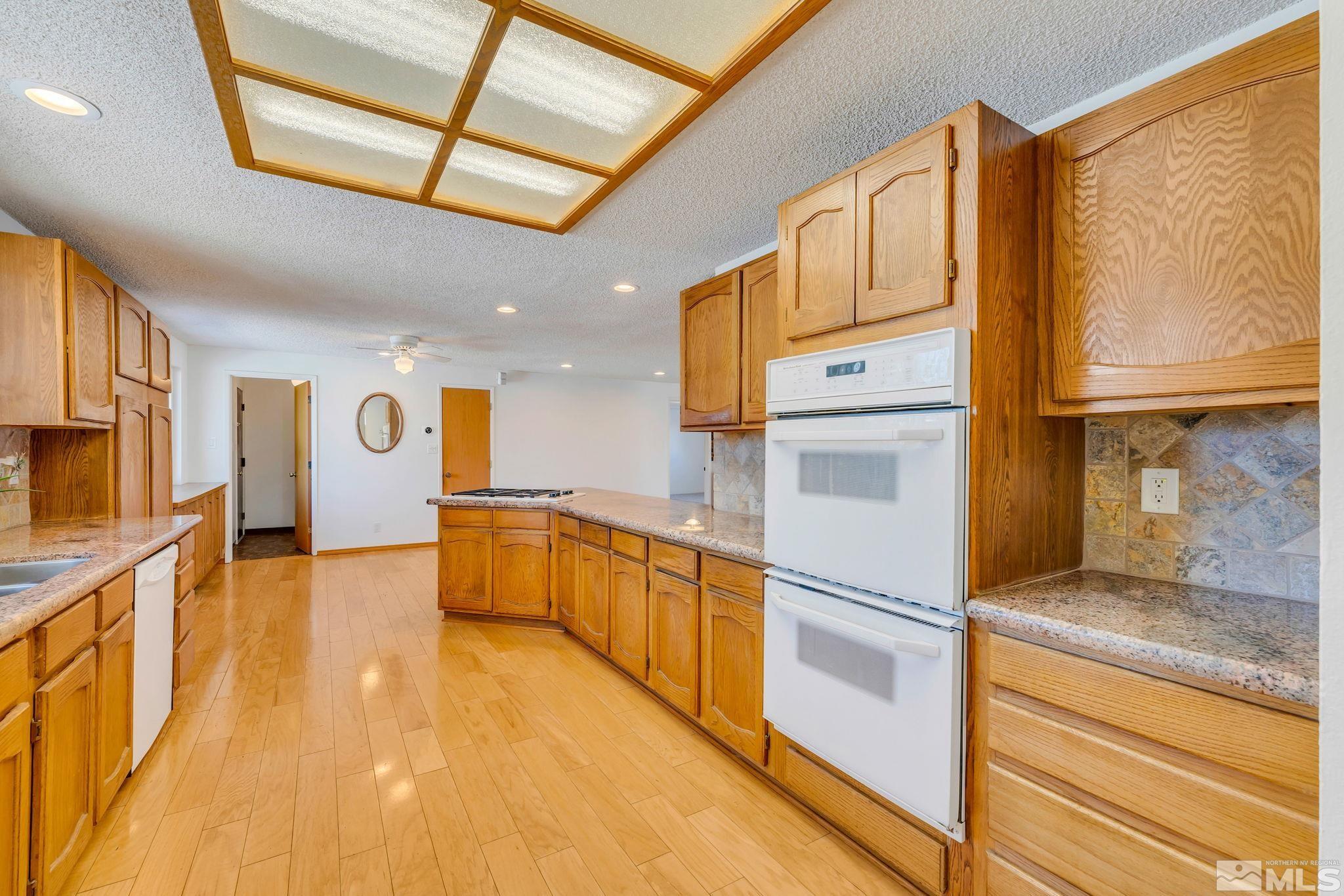 2047 Regent Street Reno, NV 89509 - Photo 8 of 28 a kitchen with stainless steel appliances granite countertop a refrigerator a oven and white cabinets with wooden floors