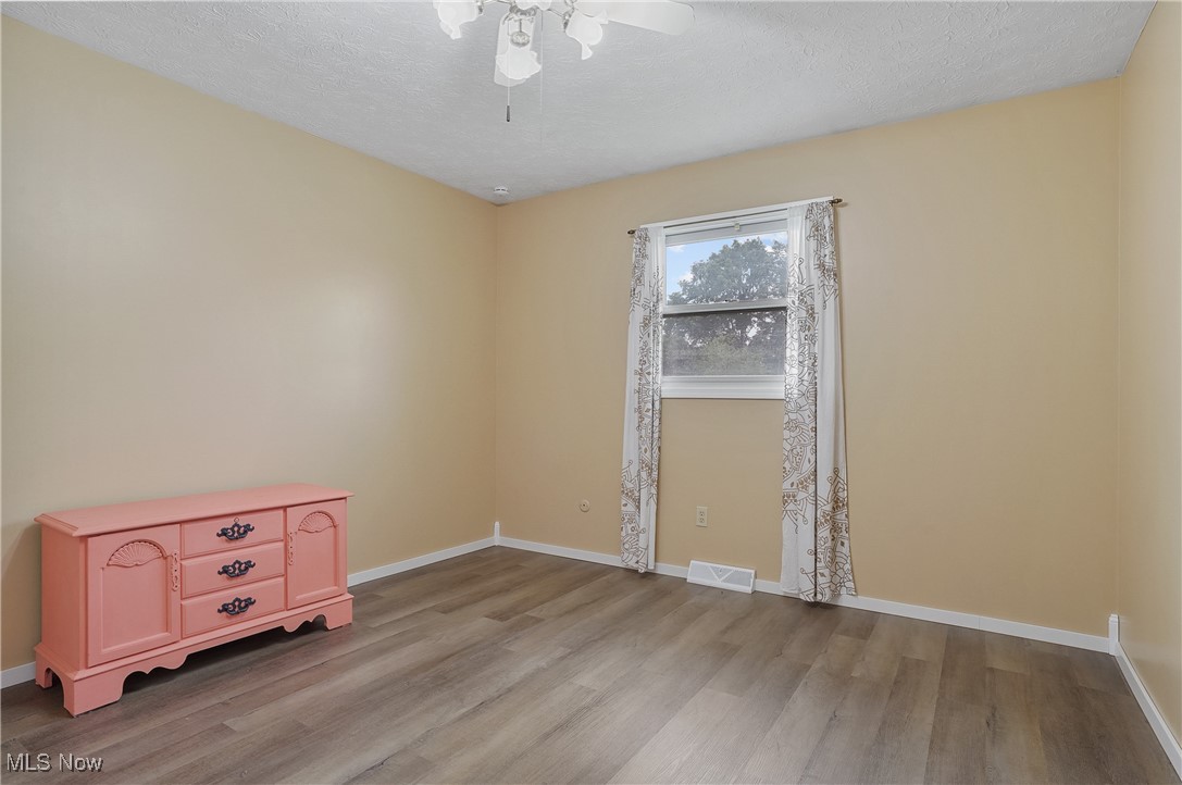 3262 Wright Road Northwest Uniontown, OH 44685 - Photo 26 of 37 Unfurnished room with light wood-style floors, ceiling fan, and a textured ceiling