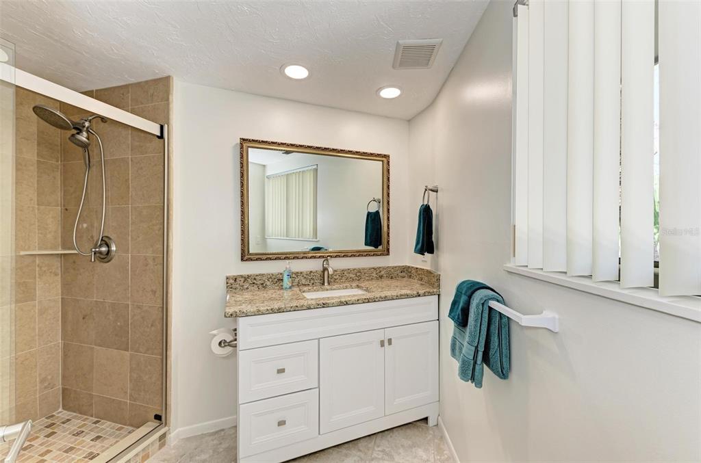 6590 Manasota Key Road Englewood, FL 34223 - Photo 28 of 69 a bathroom with a granite countertop sink a mirror a vanity and a shower
