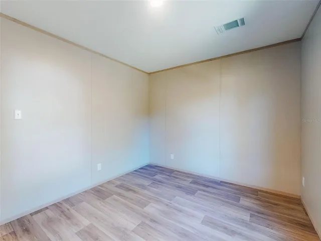 a view of a hallway with wooden floor and a bathroom