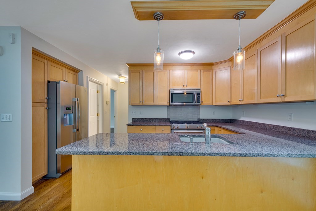 10 Rivard Road, Unit 10 Needham, MA 02492 - Photo 8 of 29 a kitchen with stainless steel appliances granite countertop a sink a stove and a refrigerator