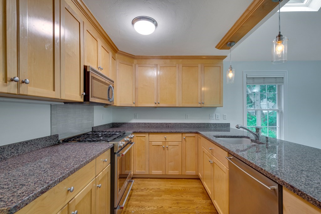 10 Rivard Road, Unit 10 Needham, MA 02492 - Photo 9 of 29 a kitchen that has a lot of cabinets in it with granite countertop wooden cabinets