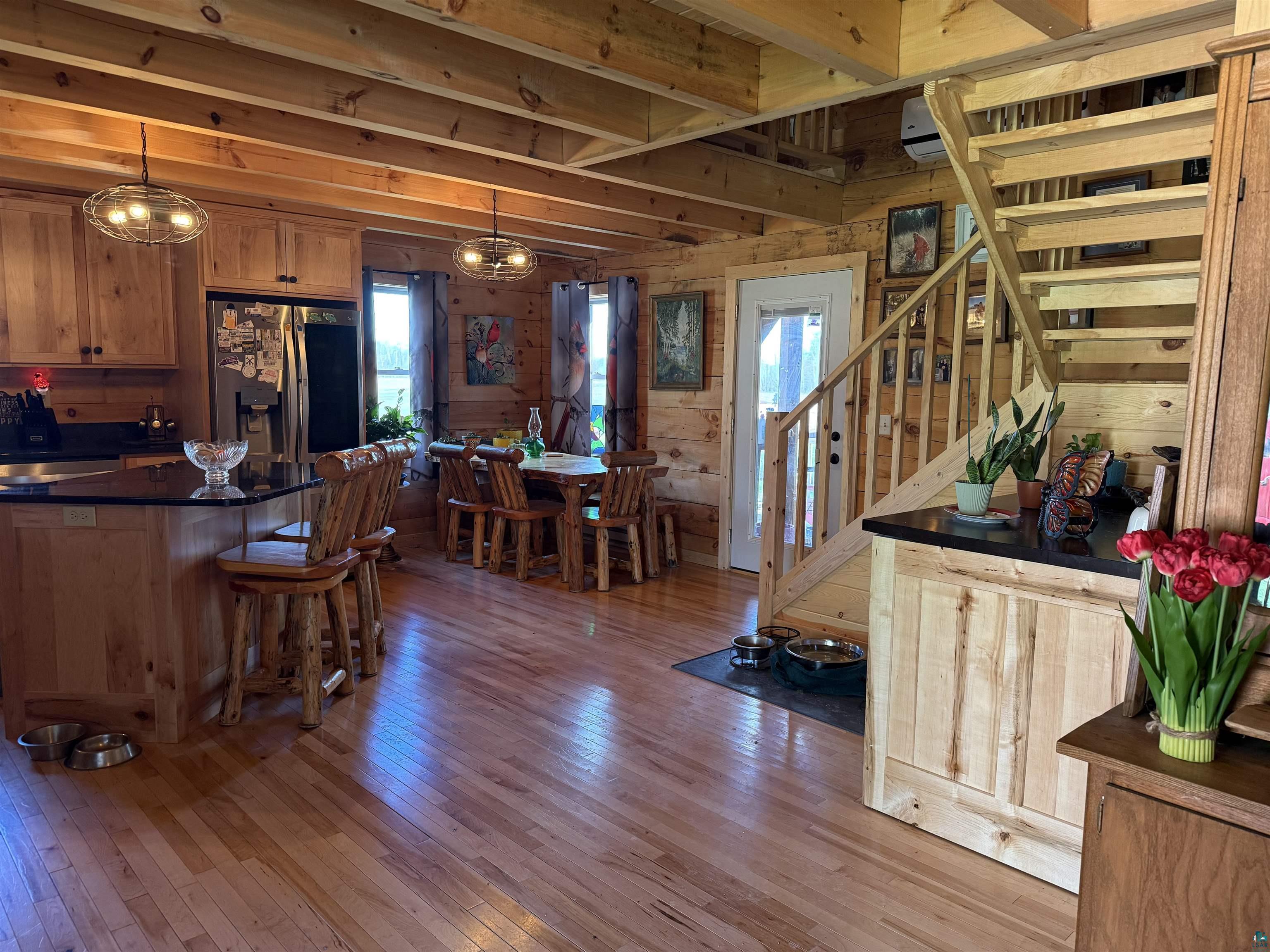 37590 Degerstrom Road Askov, MN 55704 - Photo 8 of 53 Open-concept living space featuring wood-finish flooring, exposed beam ceiling, and natural wood wall panels