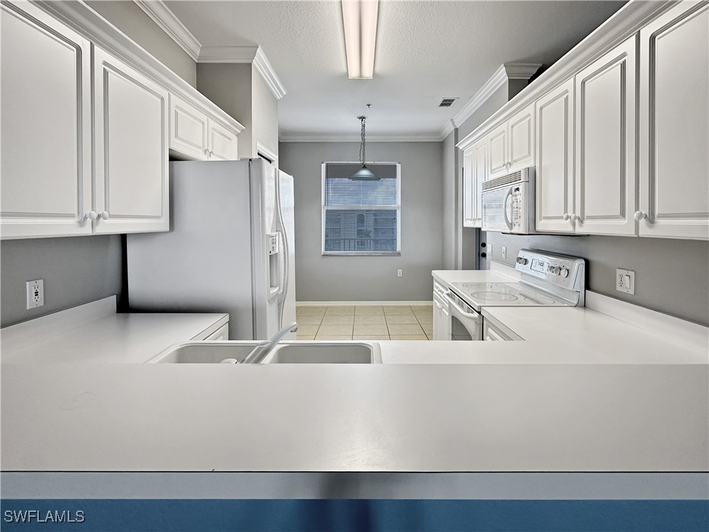 8451 Kingbird Loop, Unit 345 Estero, FL 33967 - Photo 4 of 10 a large white kitchen with a refrigerator a sink and white cabinets