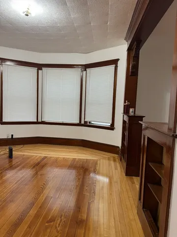 a view of an empty room with wooden floor and cabinet