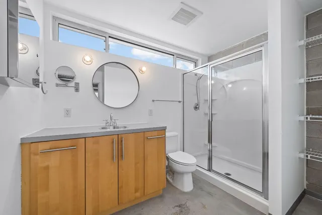 a bathroom with a double vanity sink toilet mirror and shower