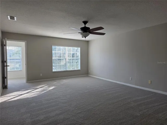 an empty room with windows and fan