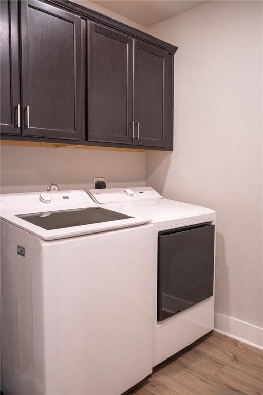 7909 Townsend Drive Waco, TX 76708 - Photo 19 of 22 Laundry area featuring dark wood cabinetry with silver hardware, white walls, and wood-finish flooring