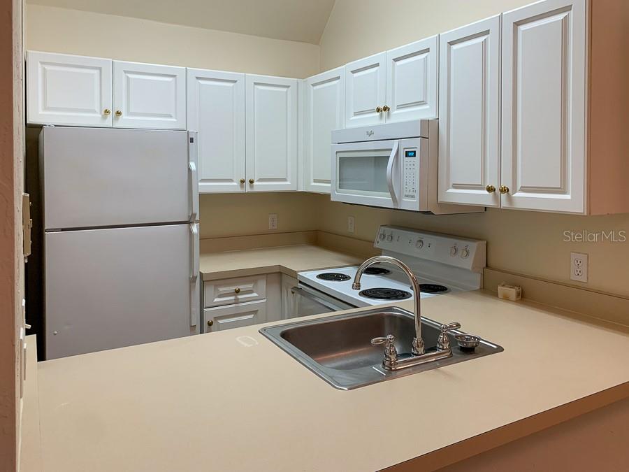 3901 Southwest 27th Street, Unit 5 Gainesville, FL 32608 - Photo 3 of 15 a kitchen with a sink a stove and white cabinets