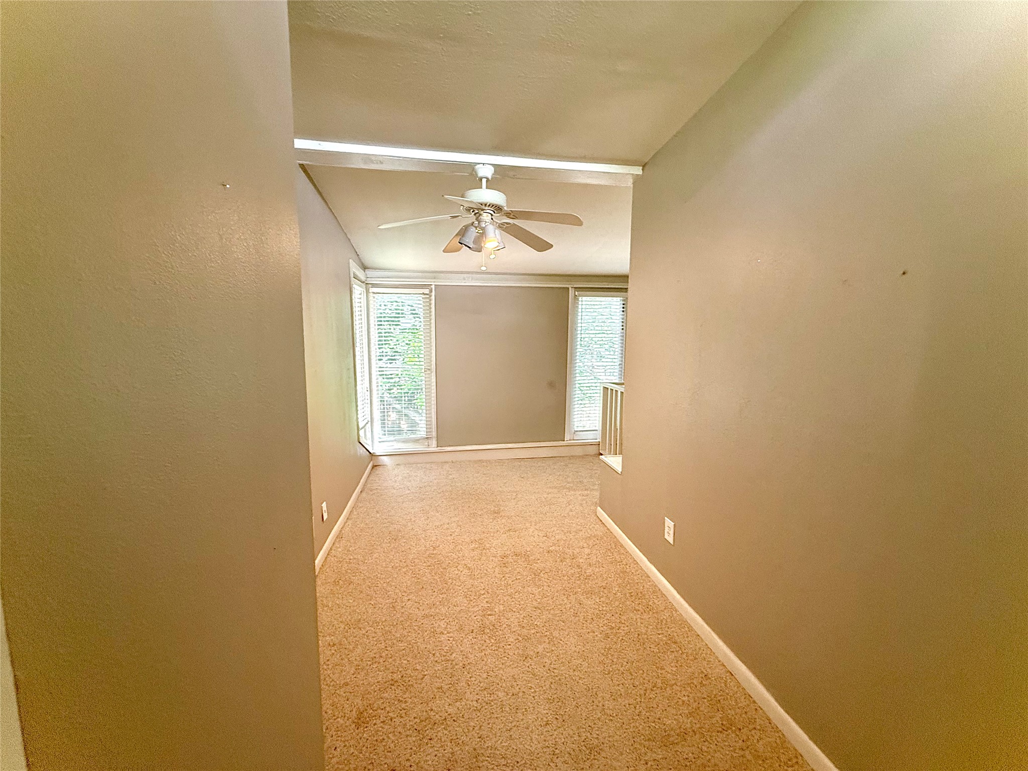 423 South Main Street Lockhart, TX 78644 - Photo 21 of 26 Carpeted room featuring a ceiling fan with light fixture, bay windows, and neutral wall tones