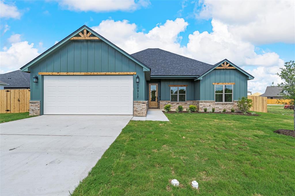 View of front facade featuring board and batten siding, roof with shingles, concrete driveway, an attached garage, and stone siding