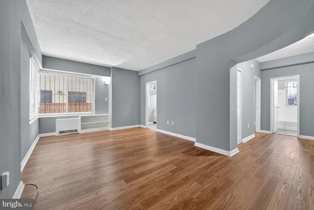 a view of an empty room with wooden floor and a window