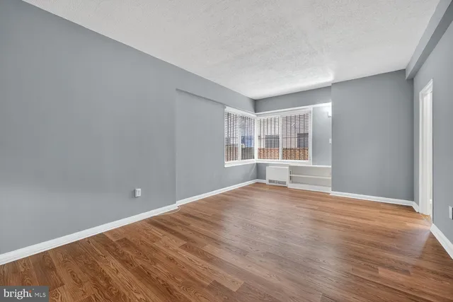 a view of an empty room with a window and wooden floor