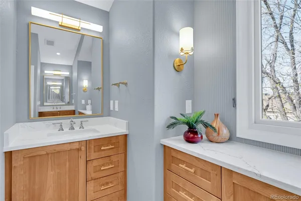 a bathroom with a granite countertop sink a window and a shower