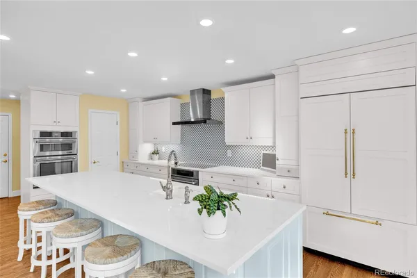 a kitchen with stainless steel appliances granite countertop a sink a stove a refrigerator and a dining table with wooden floor